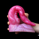 Oktopus-Buttplug auf Handfläche; geschwungene Form, Saugnoppen-Details am Fußteil, pink/lila
