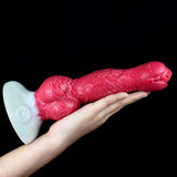 Dog-shaped sex toy (red), long textured body, white tail fin, knot near mid-base