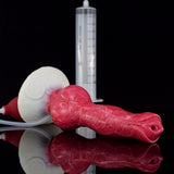 Pink canine-shaped dildo on its side with suction base, syringe body and clear hose