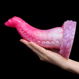 Octopus tentacle butt plug held in hand, curved pink body with ribbed texture