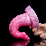 Octopus tentacle butt plug close-up, curved pink translucent with suction-cup ridges