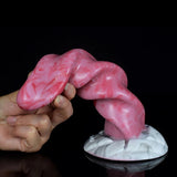 Hand holding pink swirled tentacle dildo; ribbed spiral body with white marble-look base