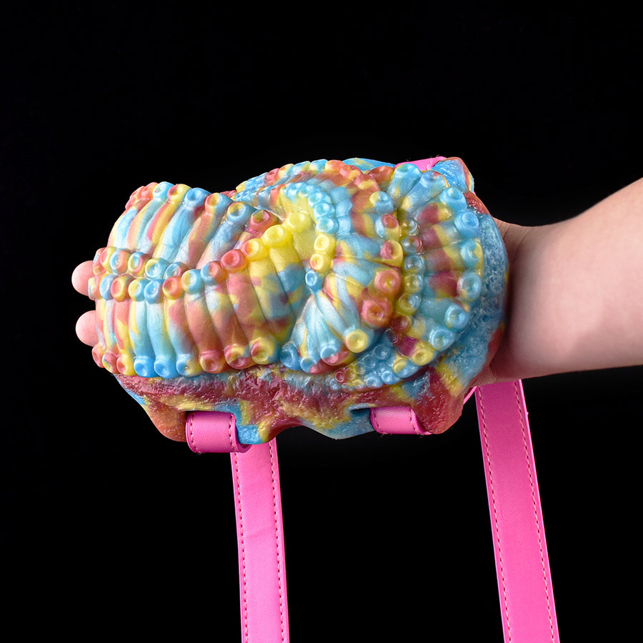 Thalis octopus grinder toy with rainbow plush body and pink side straps, held in hand